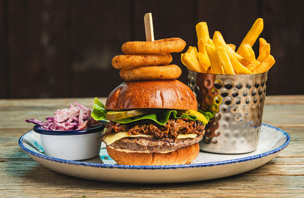 Pulled beef burger with onion rings, fries and slaw